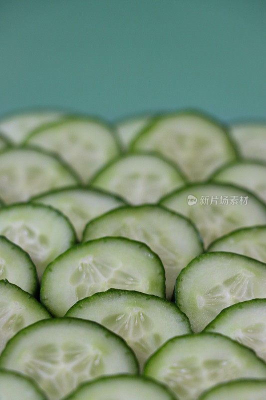 绿色背景上的多层黄瓜(Cucumis sativus)切片的特写图像，绿色皮肤和白色果肉与白色种子的鱼鳞图案展示，健康饮食海报壁纸背景设计，抬高视图，复制空间